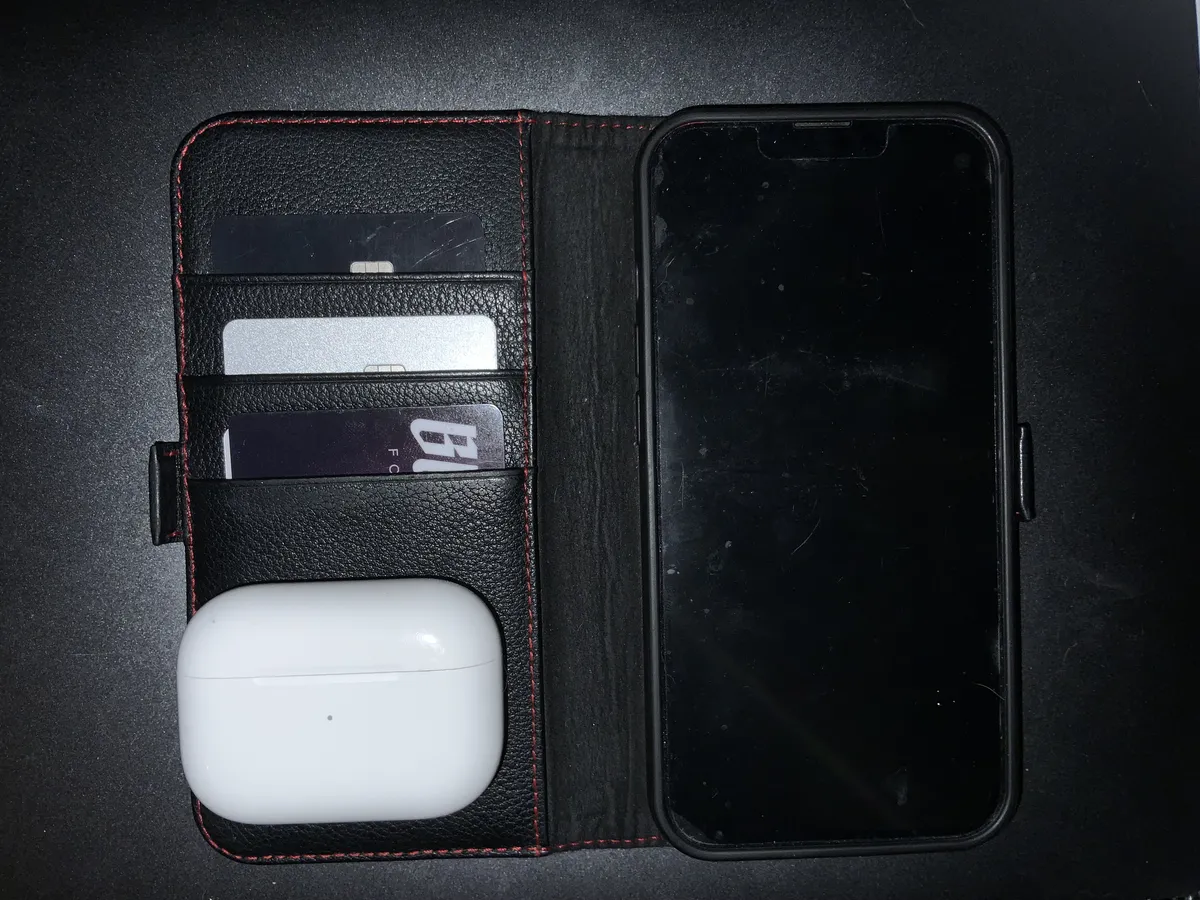 A picture showing an iPhone in fold out case with card inserts, and airpods